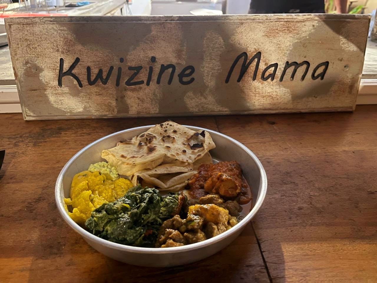 Un plateau complet devant l'enseigne Kwizine Mama : farata, curry, brèdes et rougail