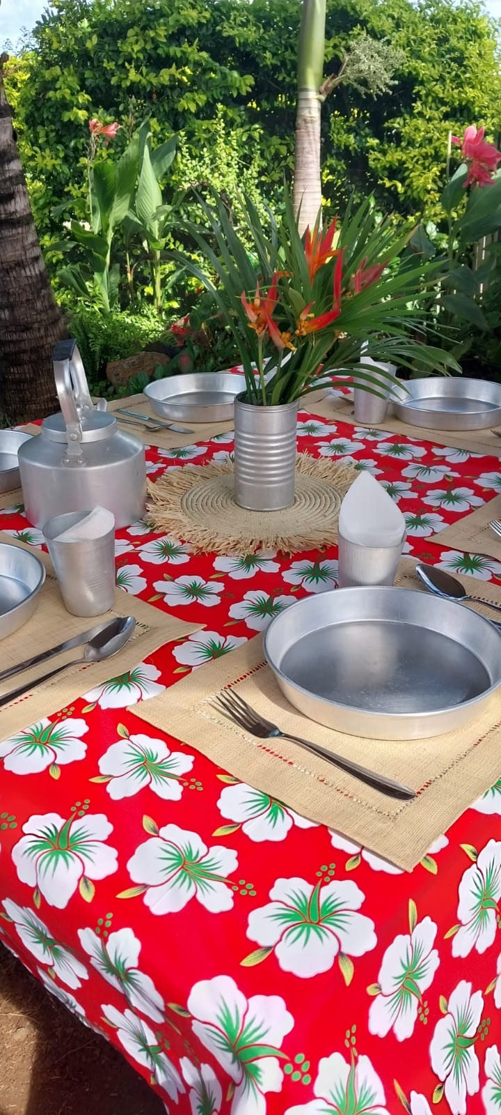 La table dressée au jardin, nappe à fleurs d'hibiscus et vaisselle en aluminium